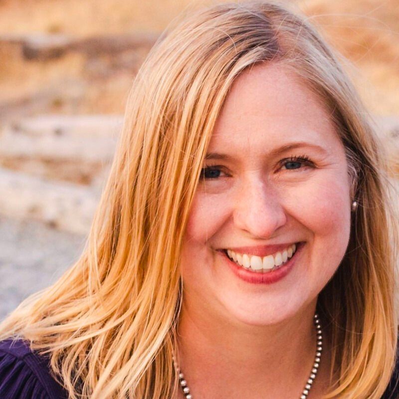Man in red hat and sunglasses smiles, with a trimmed beard.