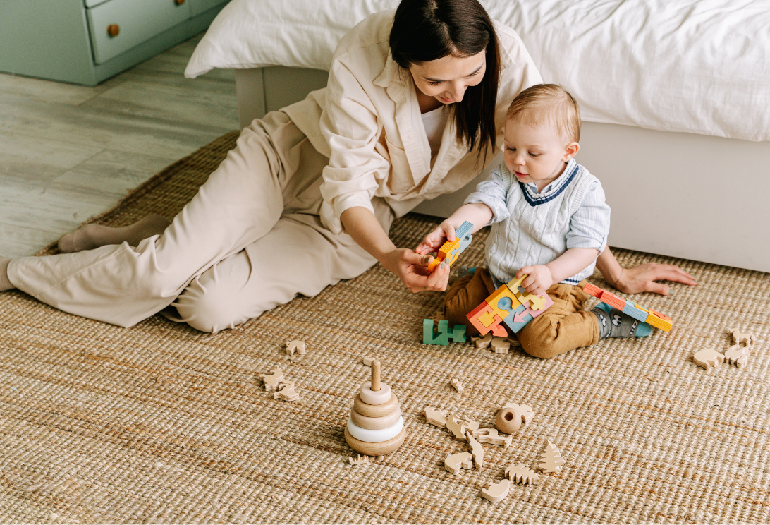 A woman is sitting on the floor playing with a baby.