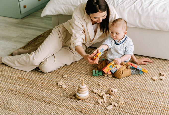 A woman is sitting on the floor playing with a baby.