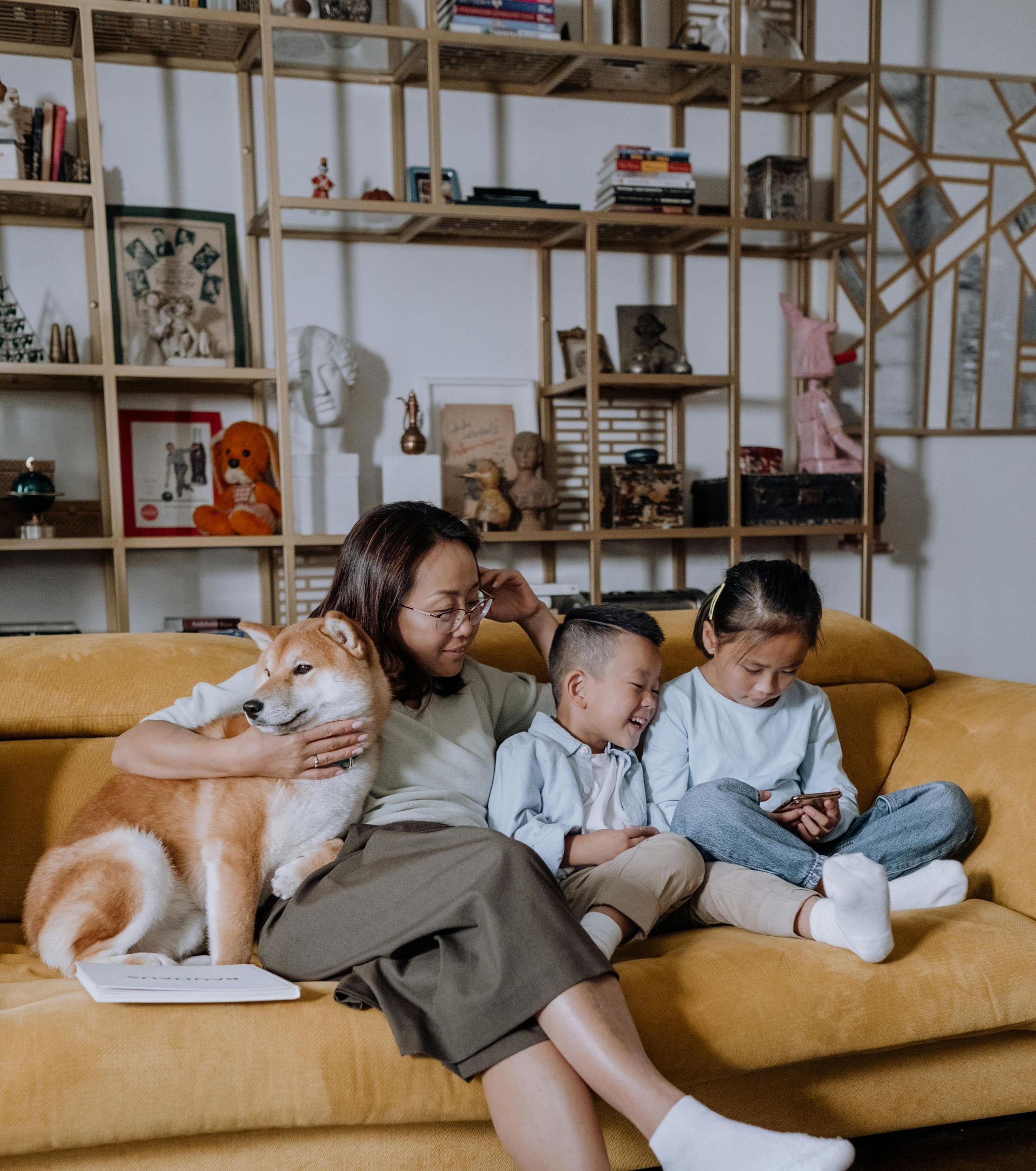 A woman is sitting on a couch with two children and a dog.