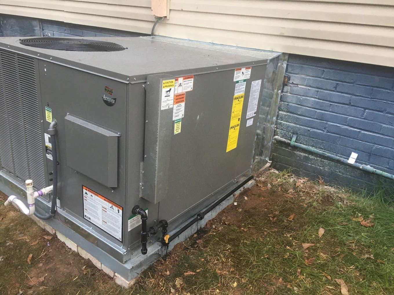A large air conditioner is sitting on the side of a house.