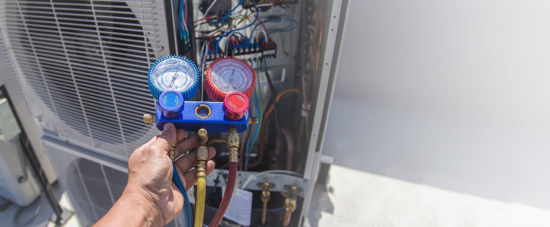 A person is holding a gauge in front of an air conditioner.