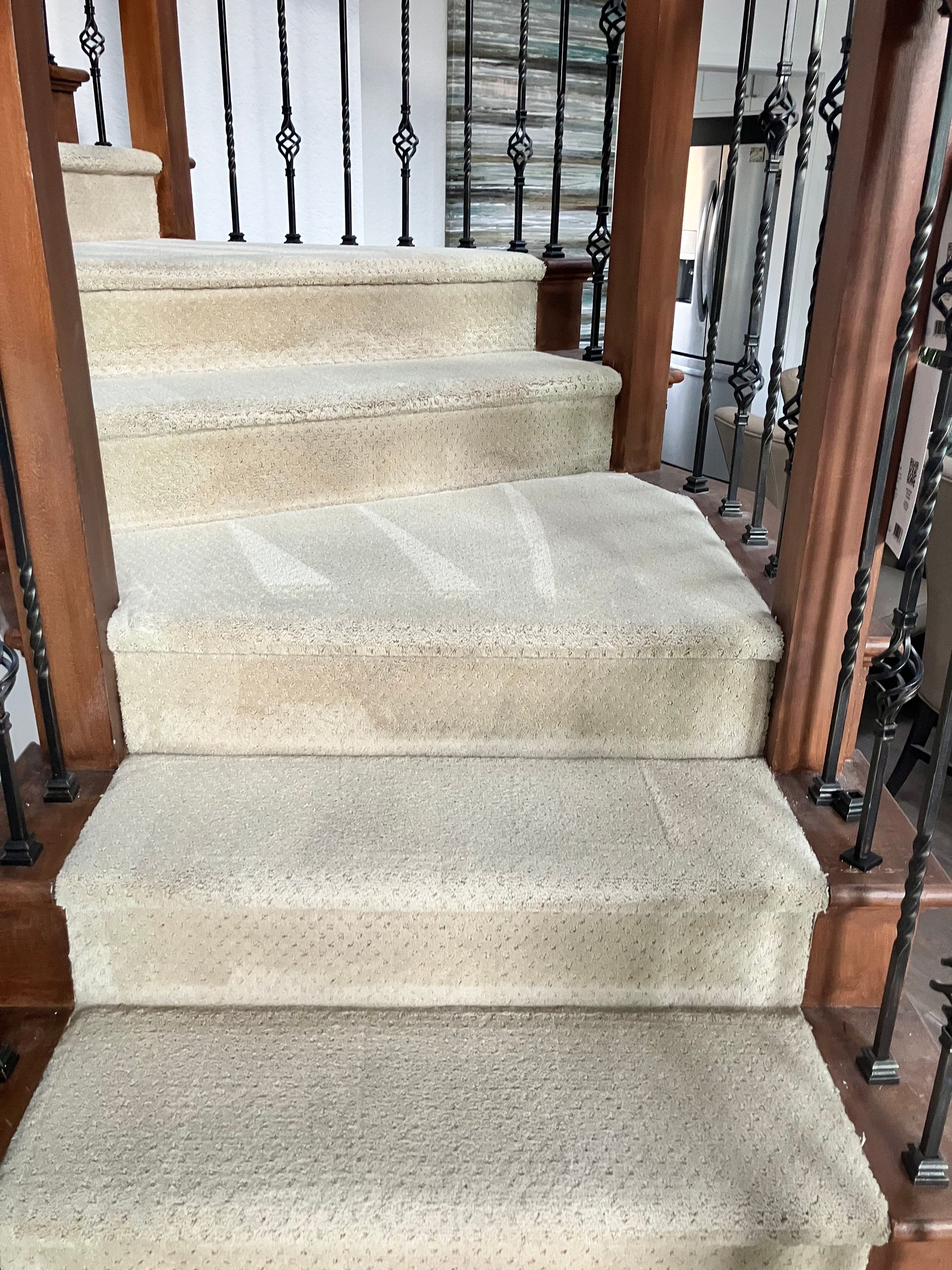 Carpeted staircase with wooden railings inside a home, viewed from the bottom up