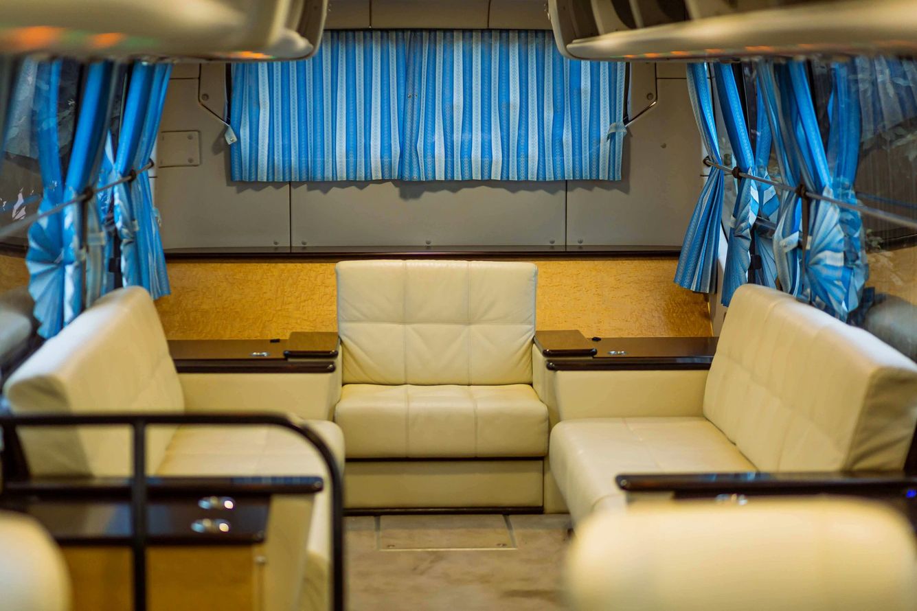 Cream-colored seating area inside a small van or RV with blue curtains and wood-paneled walls.