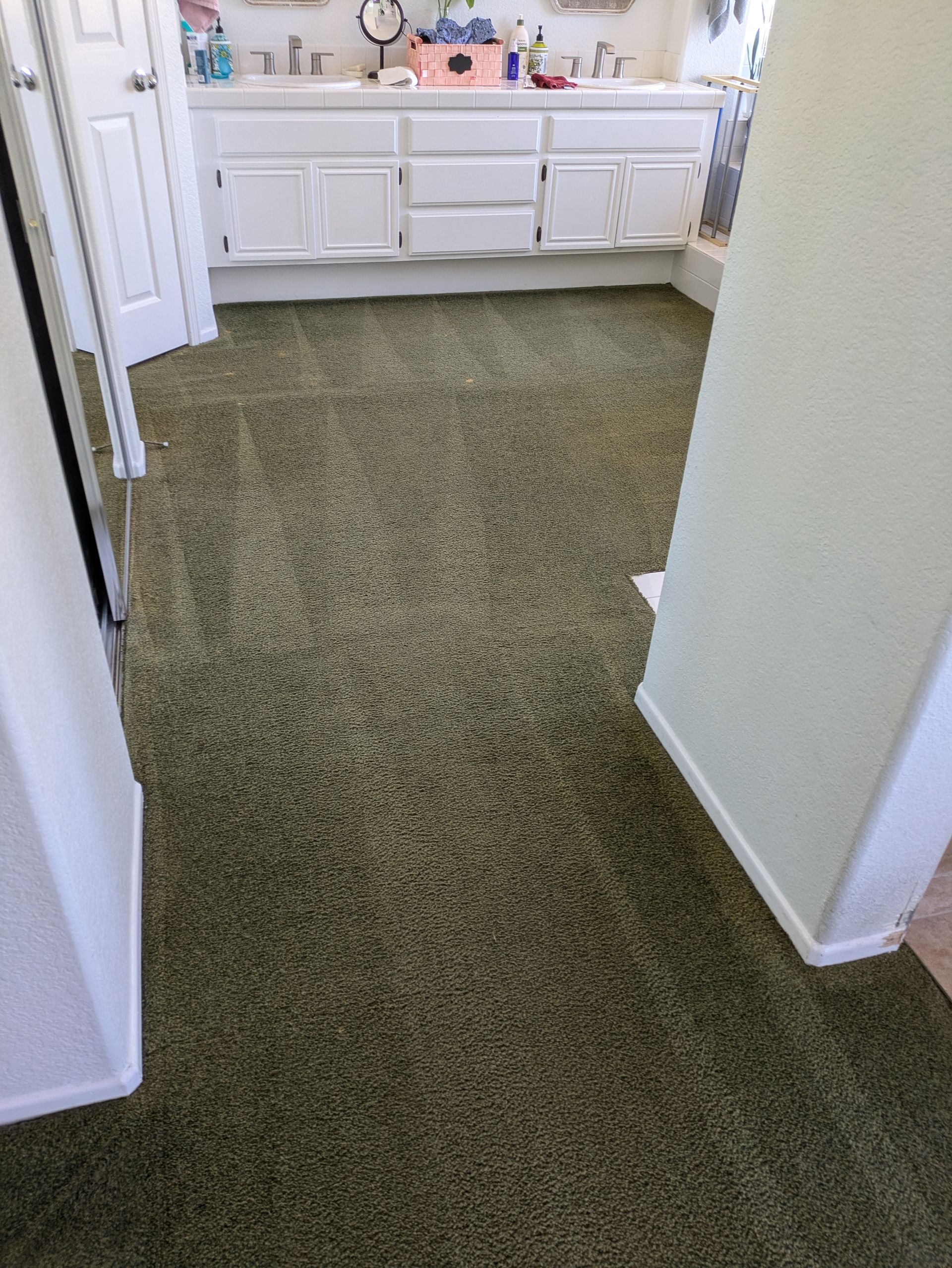 Carpeted hallway leading to a white vanity with a sink and countertop in a bathroom.