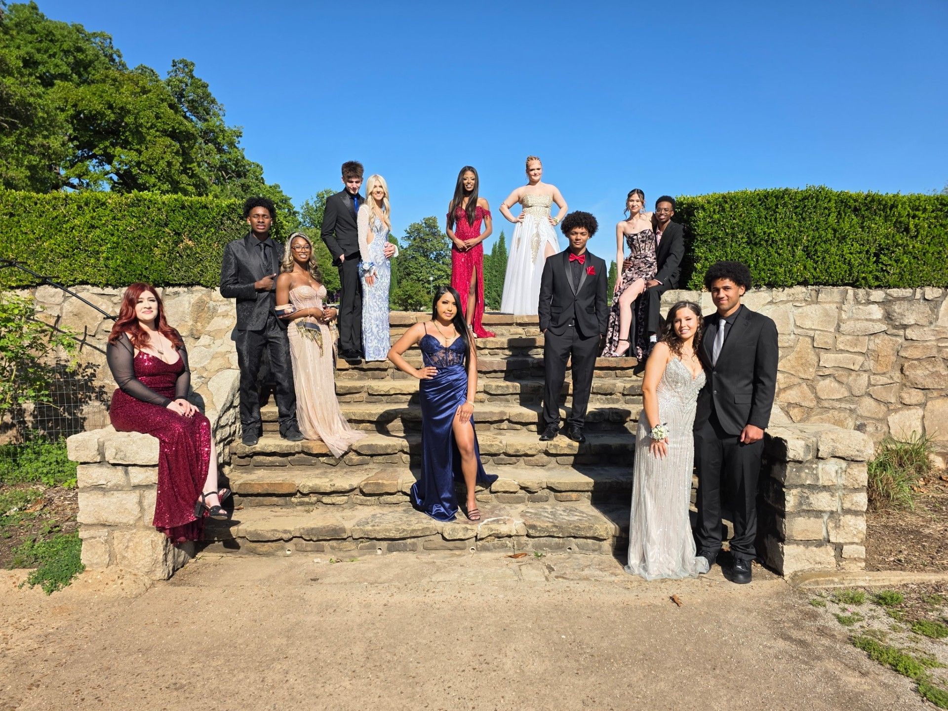 Wedding party posed on stone steps outdoors under a blue sky