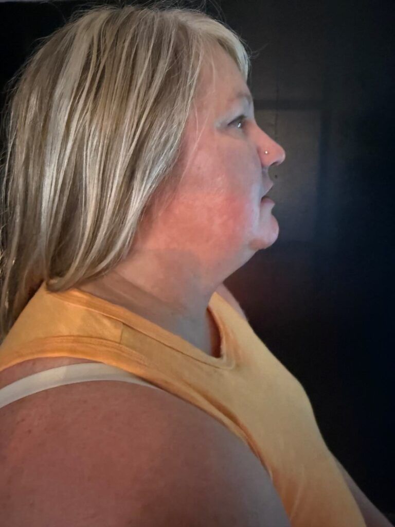 Woman in yellow top, looking right. Blonde hair, small nose ring, red cheeks.