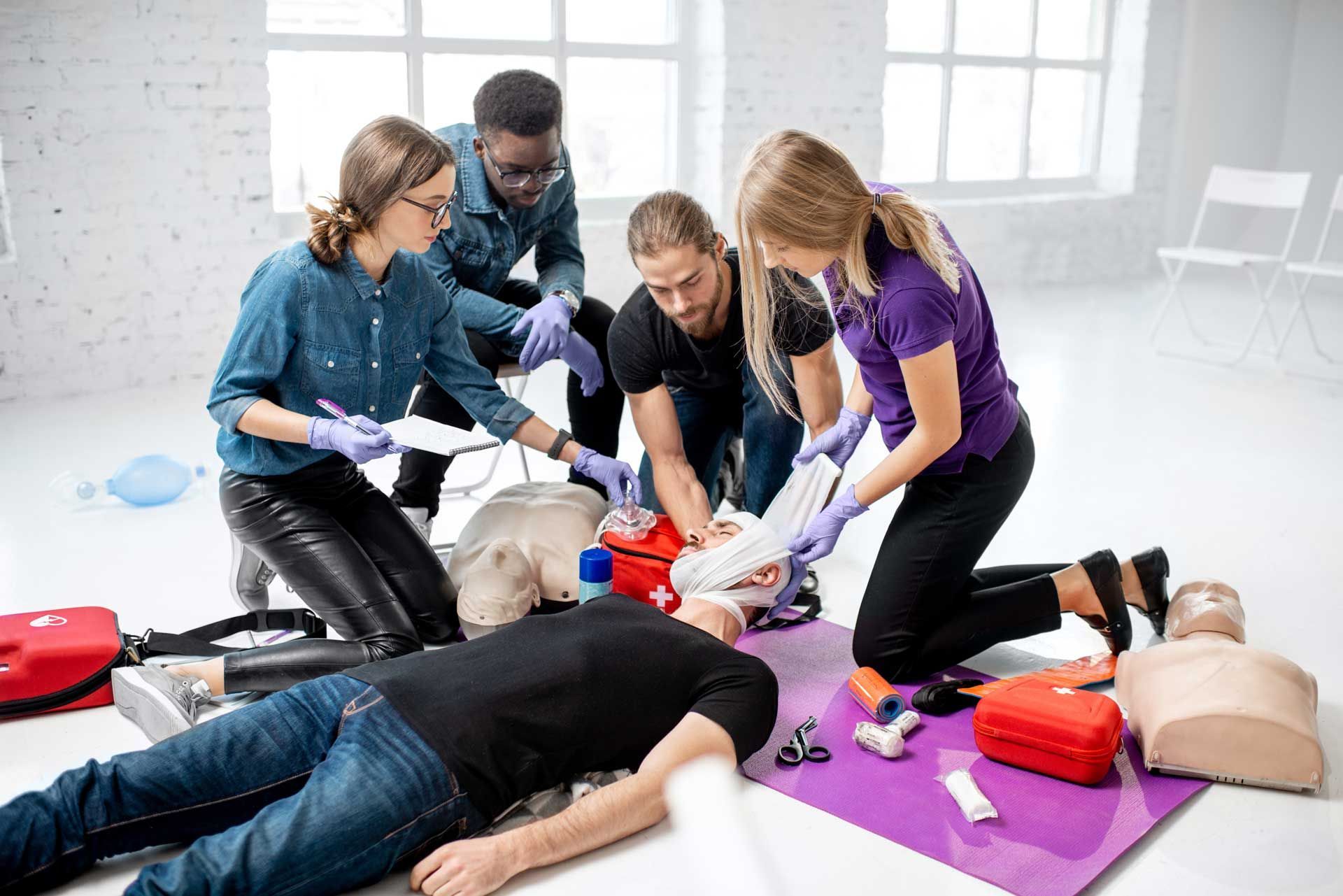 CPR training: Group of people practicing on a mannequin in a bright room.