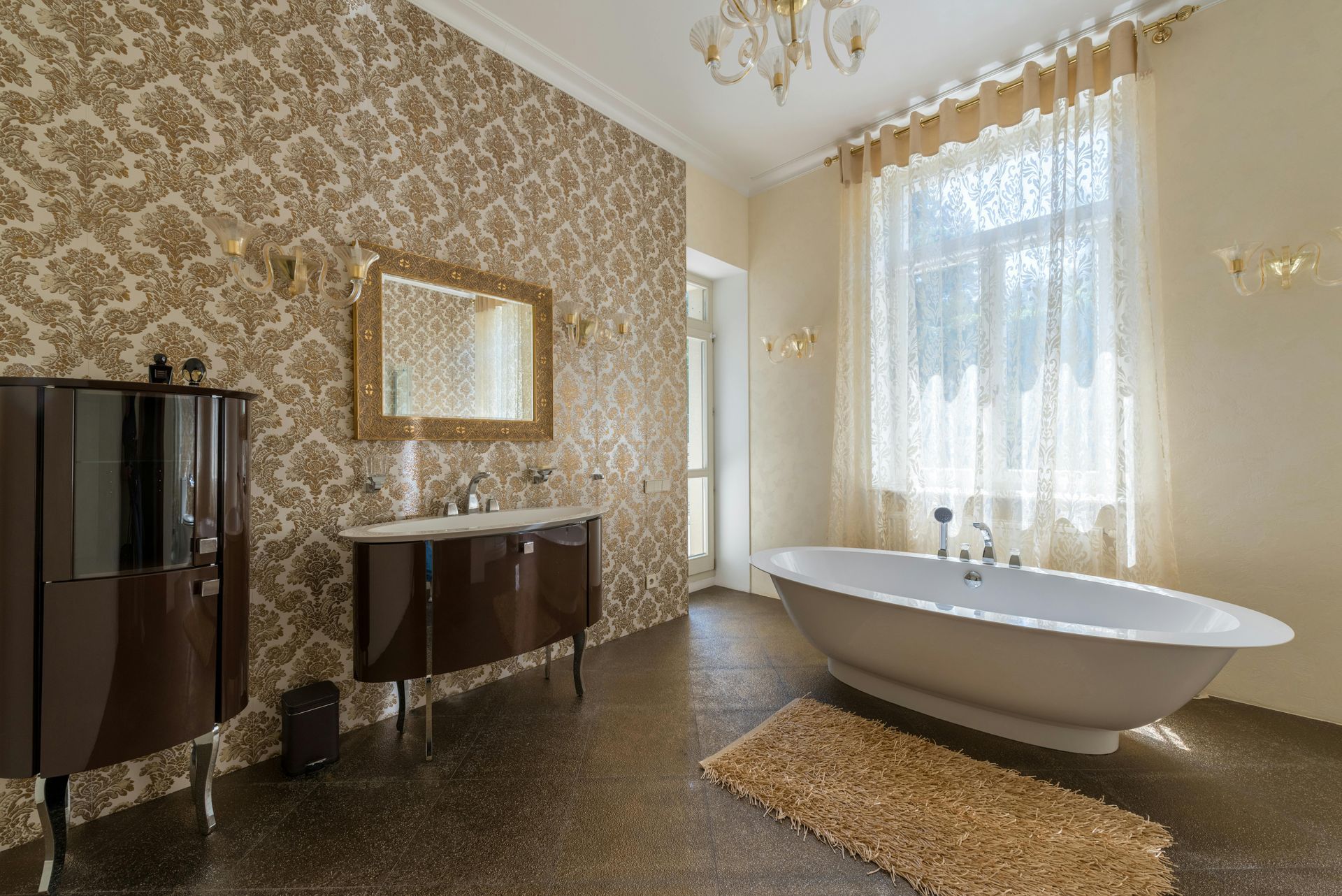 Elegant bathroom with brown cabinets, gold patterned wallpaper, and a white soaking tub.