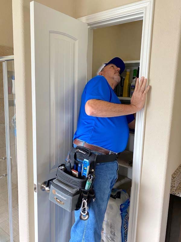 A man in a blue shirt is working on a door in a closet.