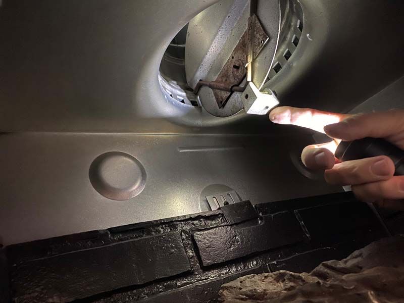 A person is holding a flashlight and pointing at a hole in the ceiling.