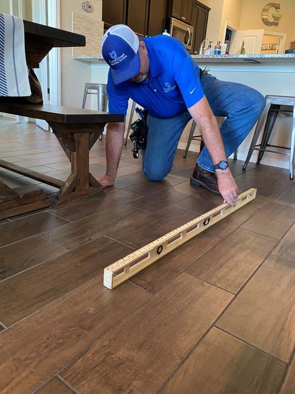 A man is measuring a wooden floor with a level.