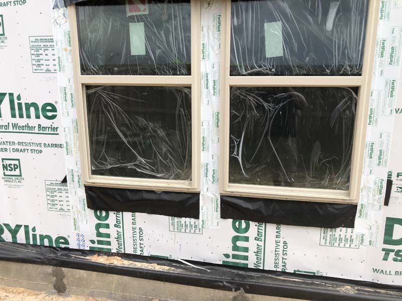 A house is being built and the windows are wrapped in plastic.
