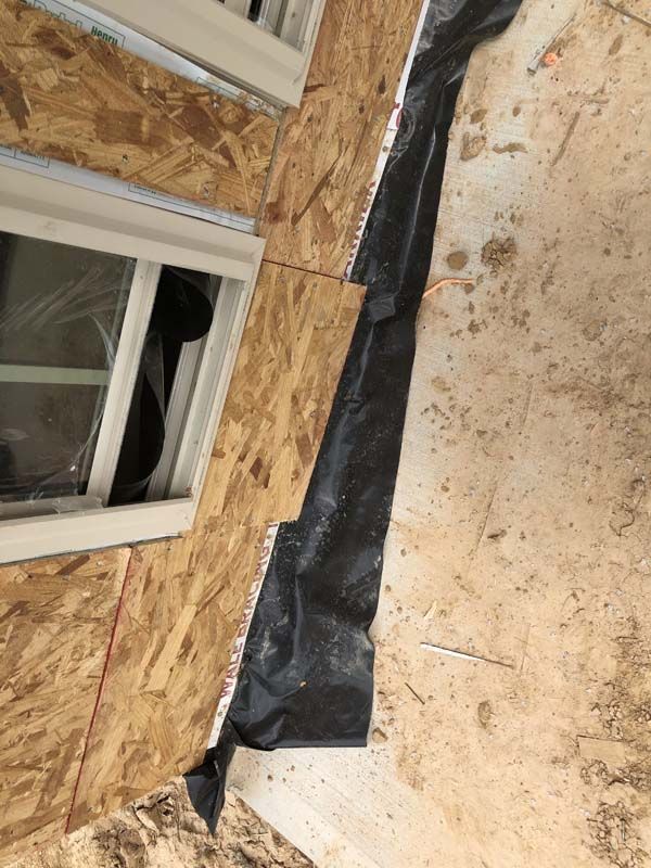 A piece of black plastic is laying on the ground next to a window.