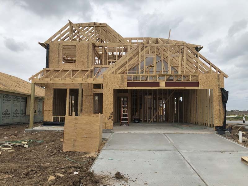 A house is being built with wooden beams and a concrete driveway.