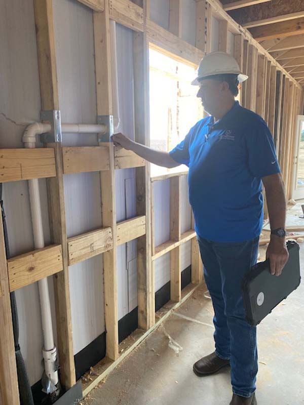 A man in a hard hat is standing in a building under construction.