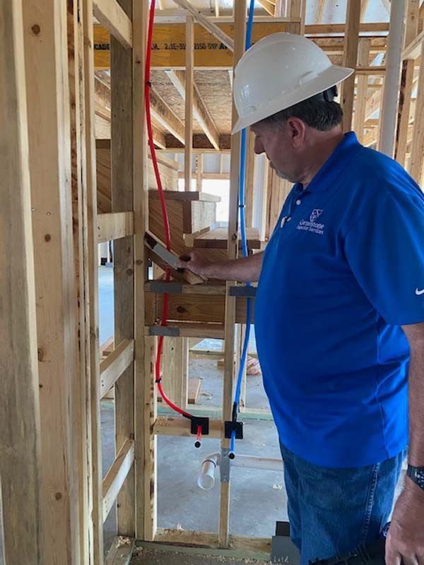 A man wearing a hard hat and a blue shirt is working on a construction site.