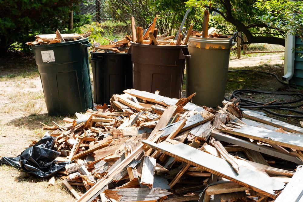 A pile of wood is sitting on the ground next to trash cans.