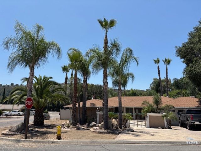 A stop sign in front of a house with palm trees