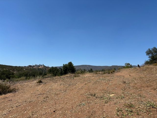 A dirt field with mountains in the background and a blue sky