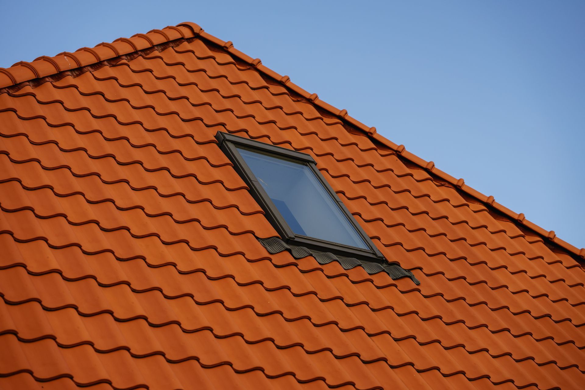 A red tiled roof with a skylight in the middle.