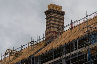 A brick chimney is sitting on top of a building under construction.