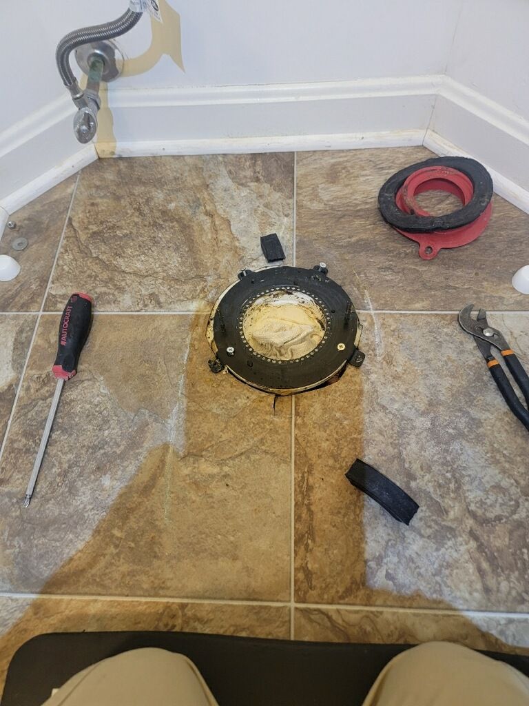 a toilet flange is being installed in a bathroom with a screwdriver and pliers .