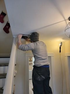 a man is working on a ceiling in a living room .