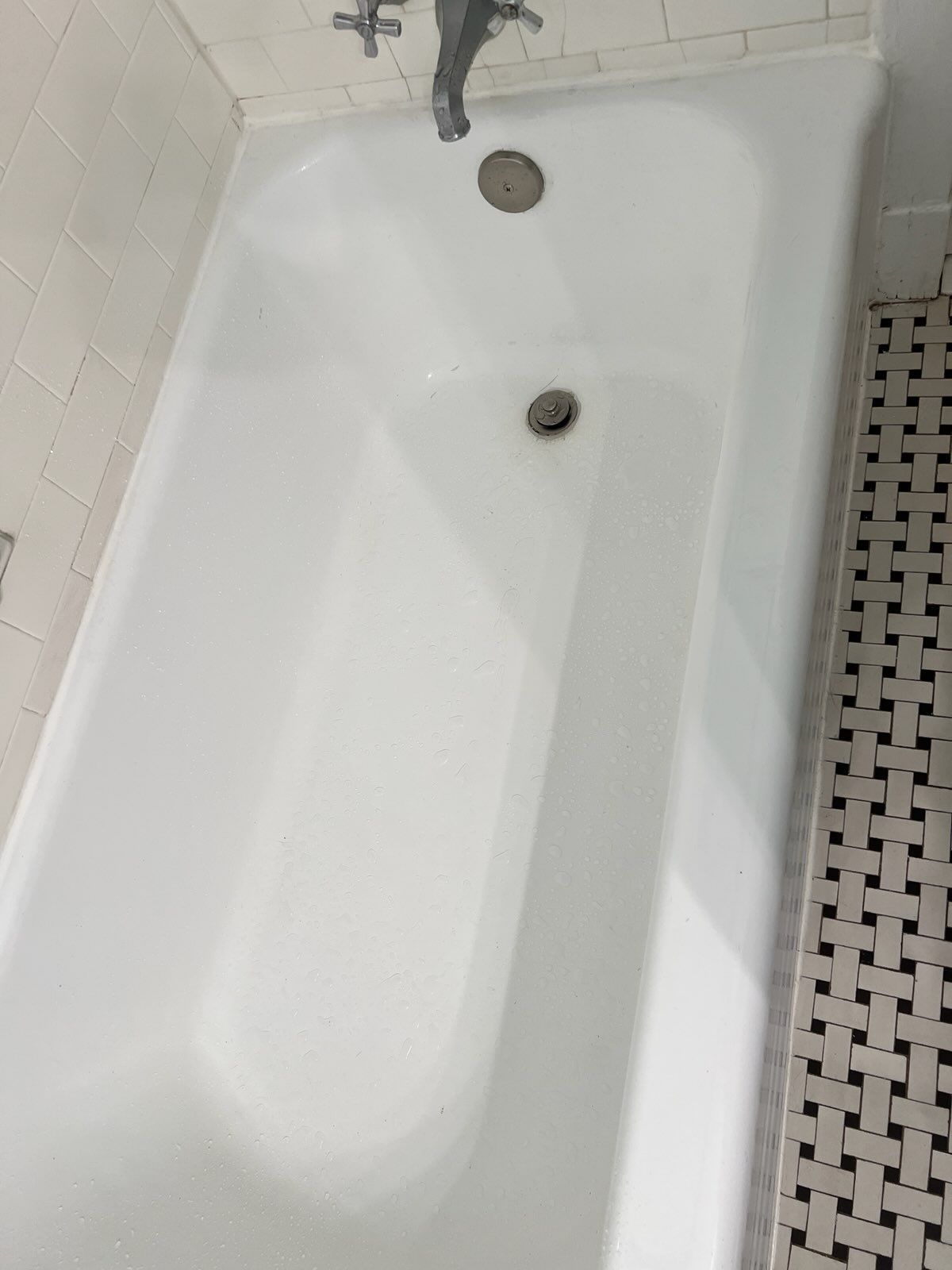 a white bathtub is sitting in a bathroom next to a tiled floor .