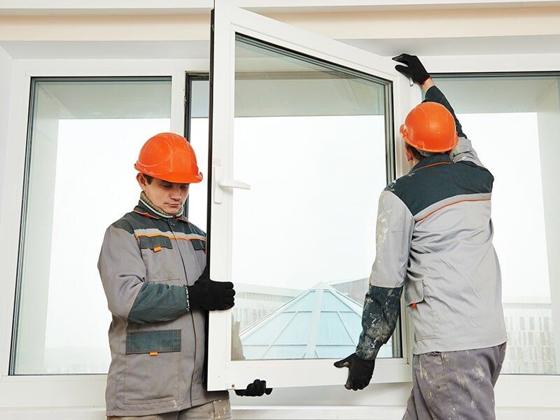 Two men installing glass window — Installation Services in Emerald, QLD