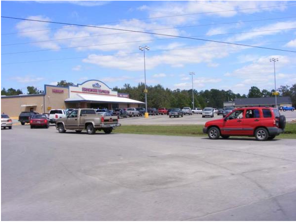 Parking lot outside a store with several cars under a partly cloudy sky