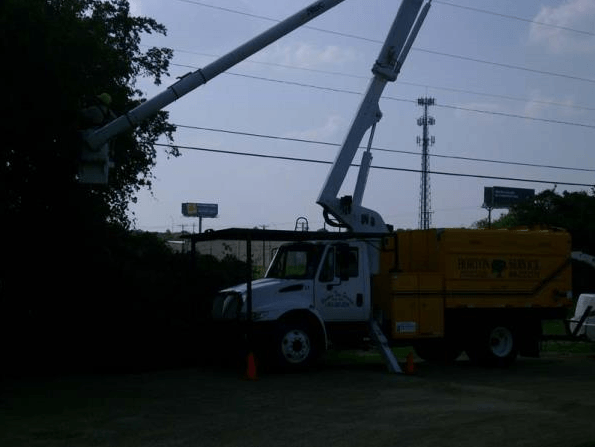 Utility truck with raised boom working near power lines at dusk