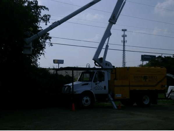 Utility truck with raised boom arm on a roadside at dusk
