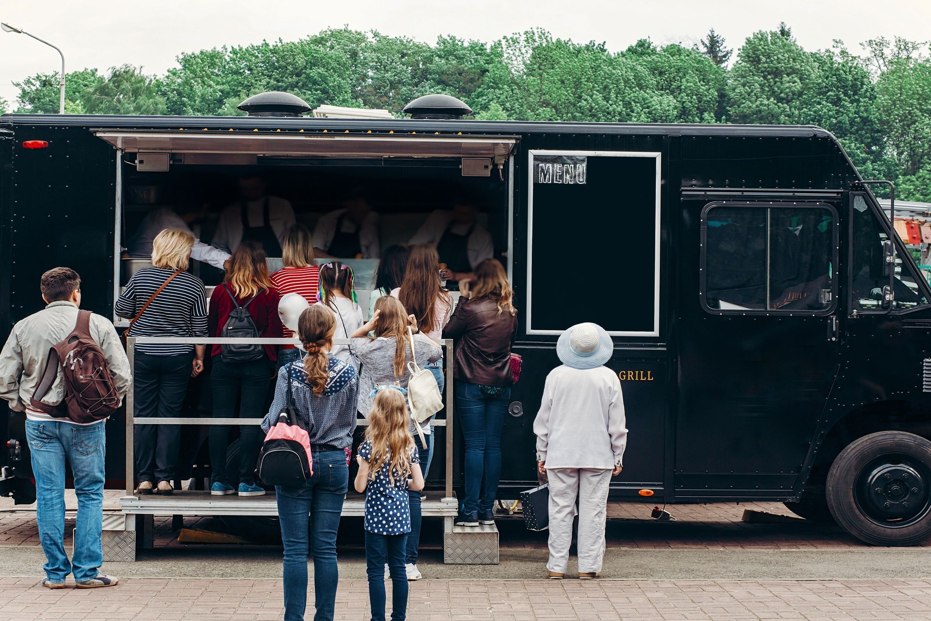 People line up to order from a black food truck.