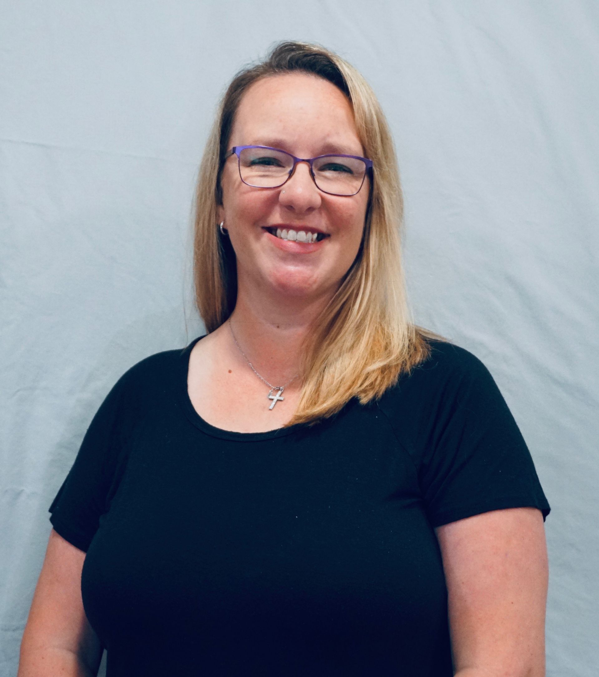 A woman wearing glasses and a black shirt is smiling for the camera.
