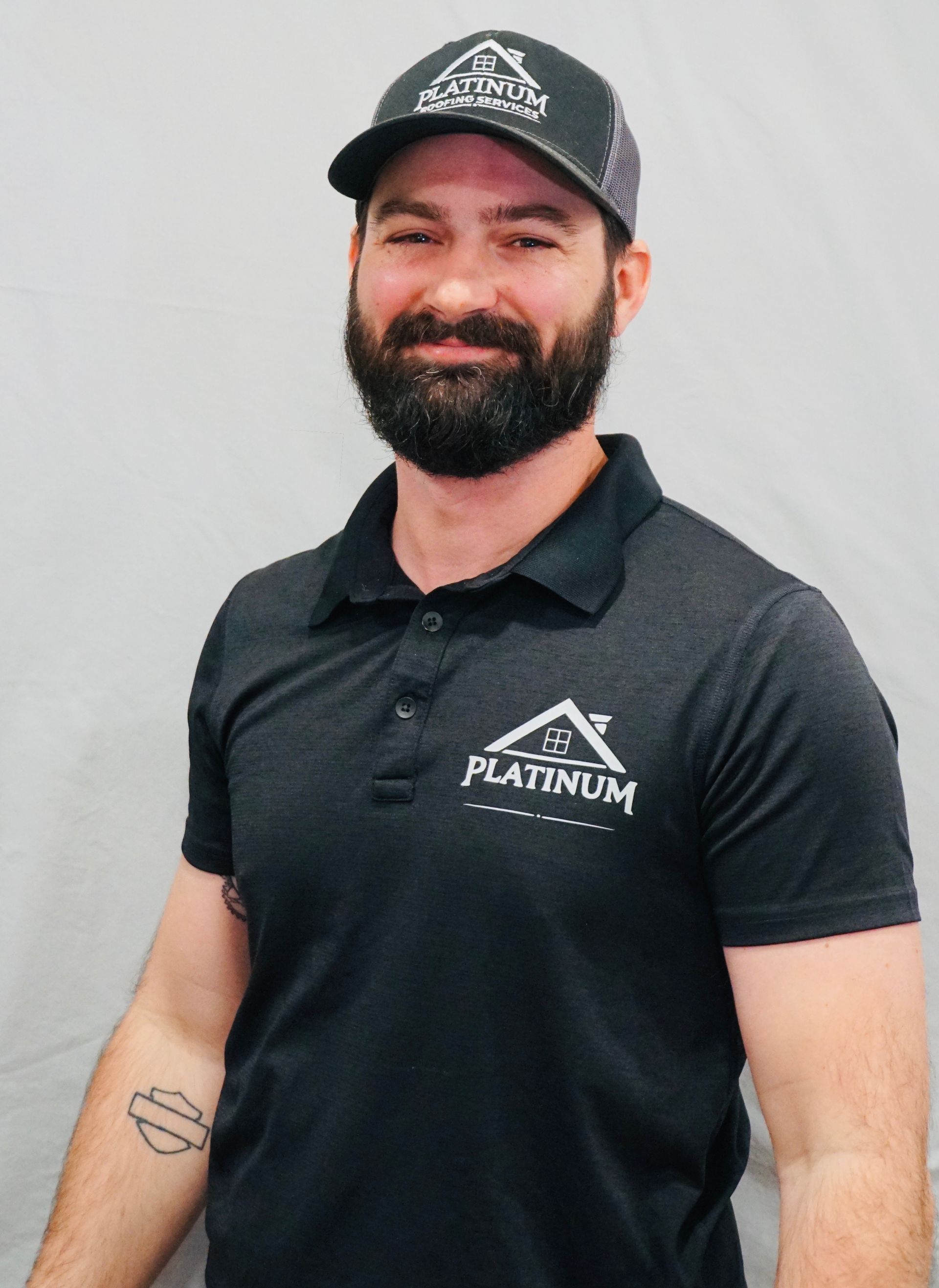 A man with a beard wearing a hat and a platinum shirt