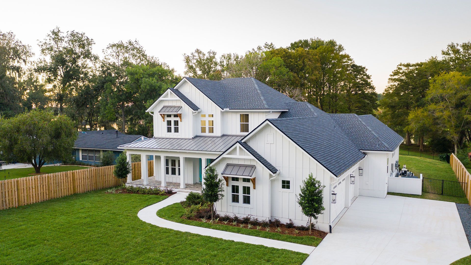 A large white house with a blue roof is sitting on top of a lush green lawn.