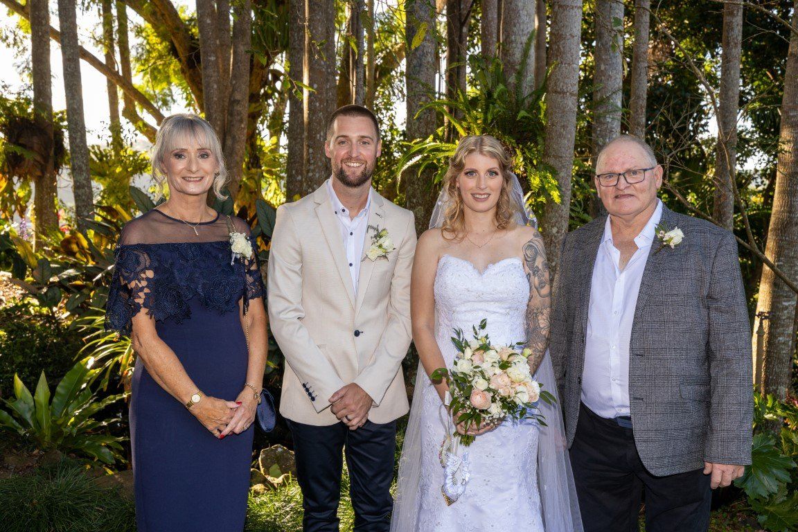 a bride and groom are posing for a picture with their parents .
