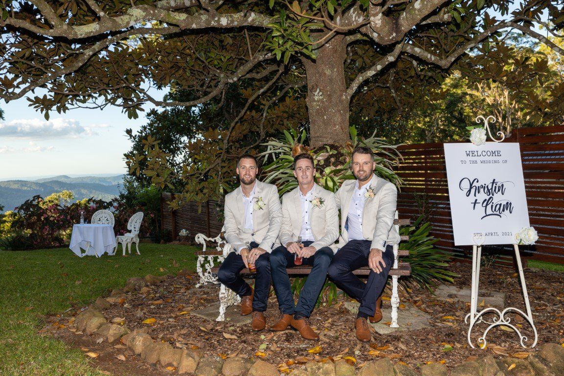 three men are sitting on a bench under a tree .