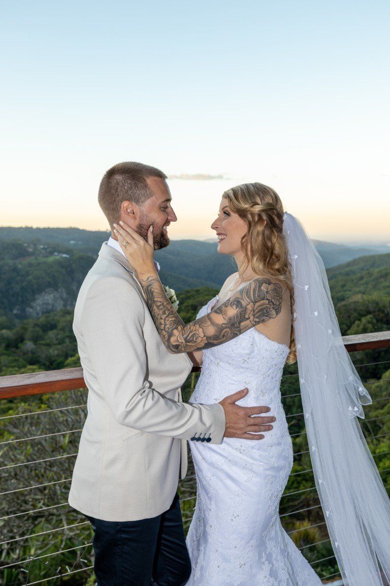 a bride and groom are standing on a balcony looking at each other .