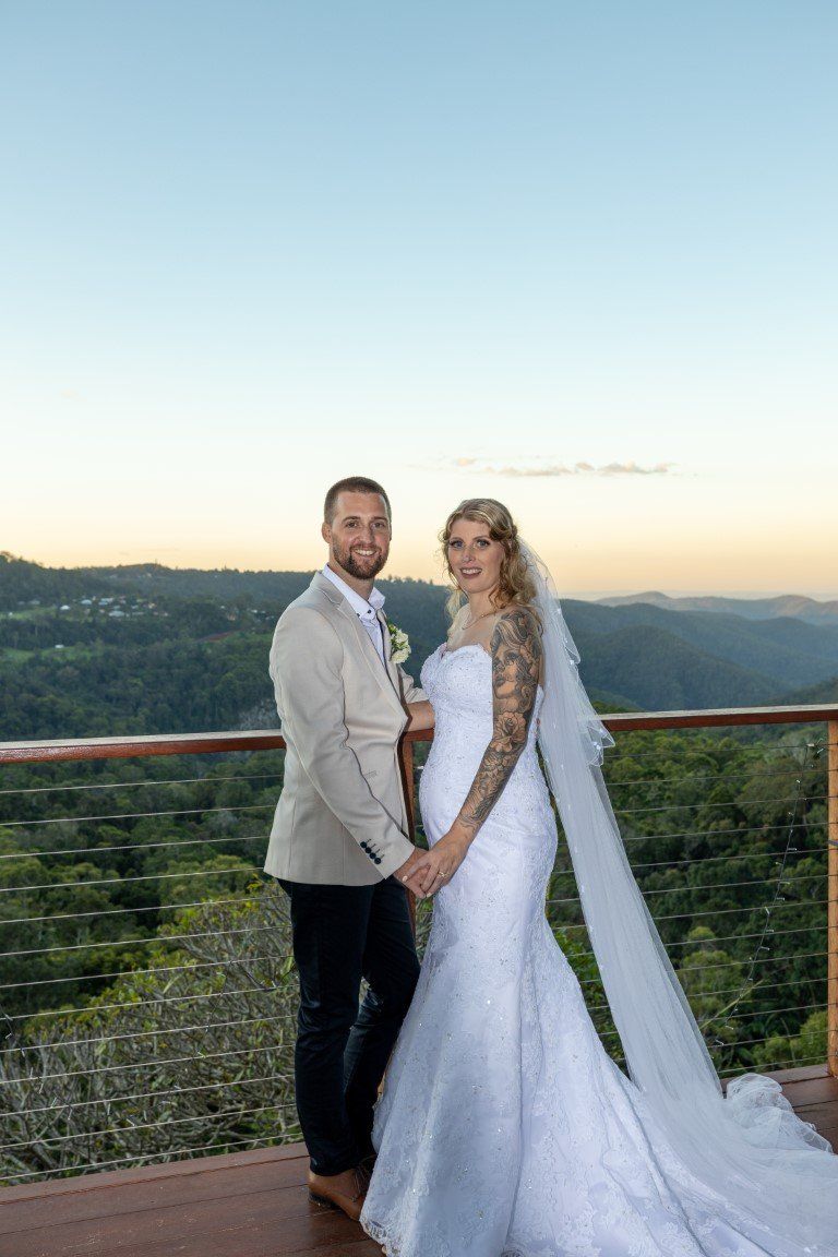 a bride and groom are standing on a balcony holding hands .