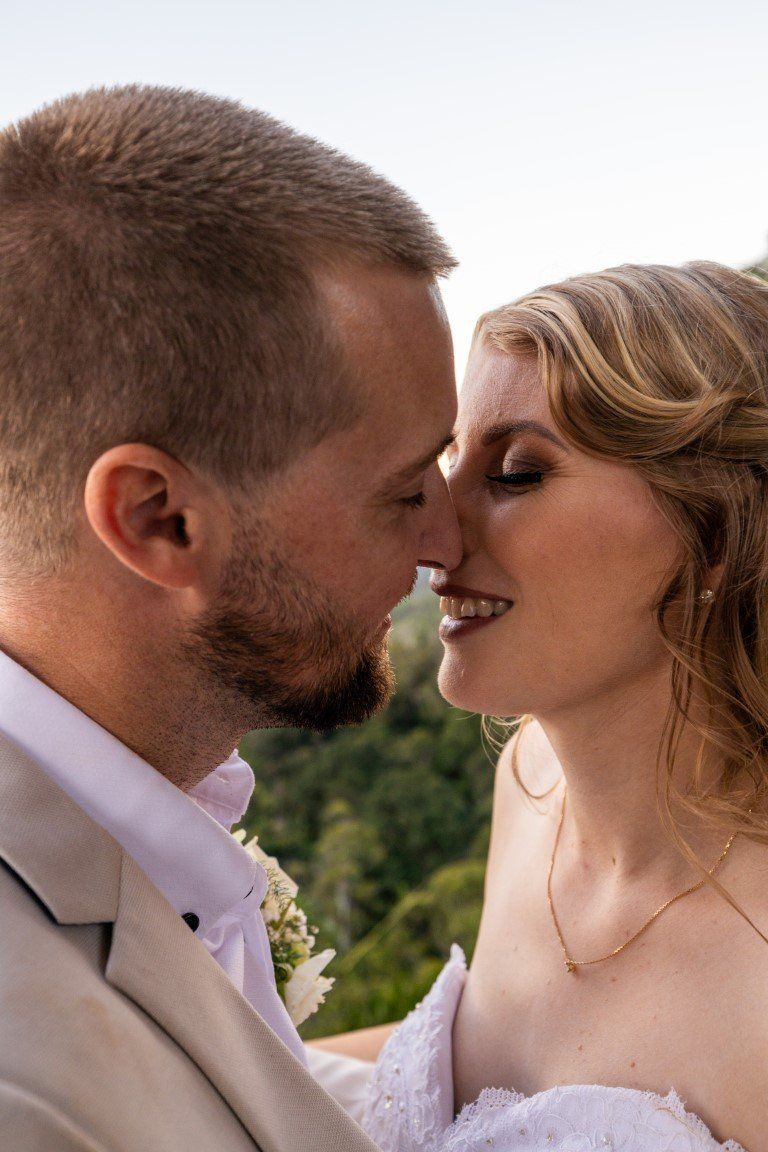 a bride and groom are kissing each other on the forehead .