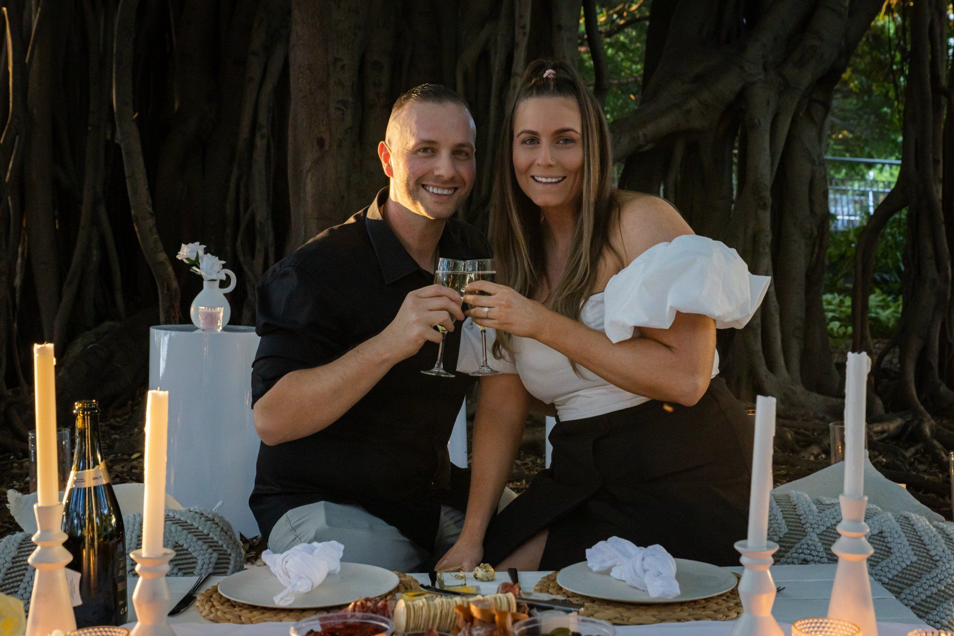 a man and a woman are sitting at a table toasting with wine glasses .