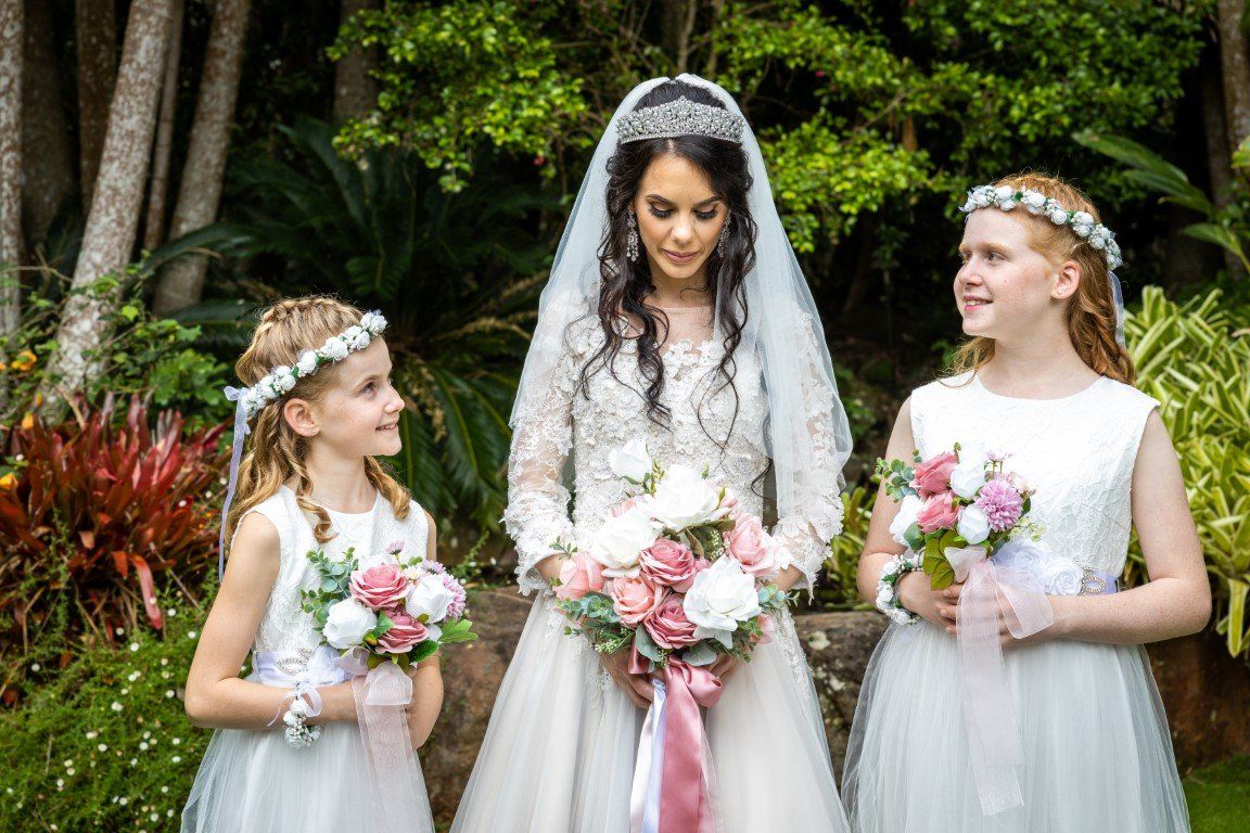 a bride and her two flower girls are posing for a picture .