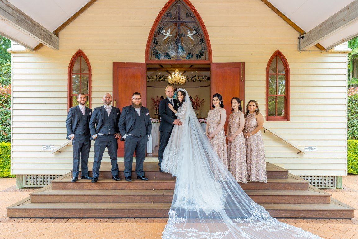 a bride and groom are posing for a picture with their wedding party in front of a church .