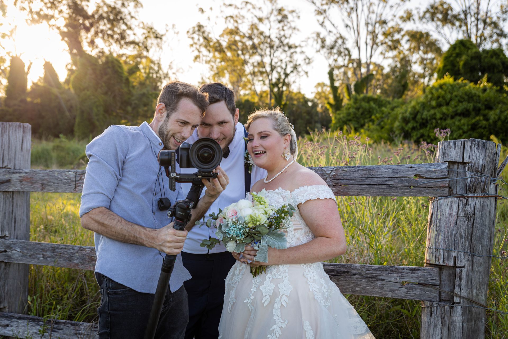 A bride and groom are posing for a picture with a cameraman.