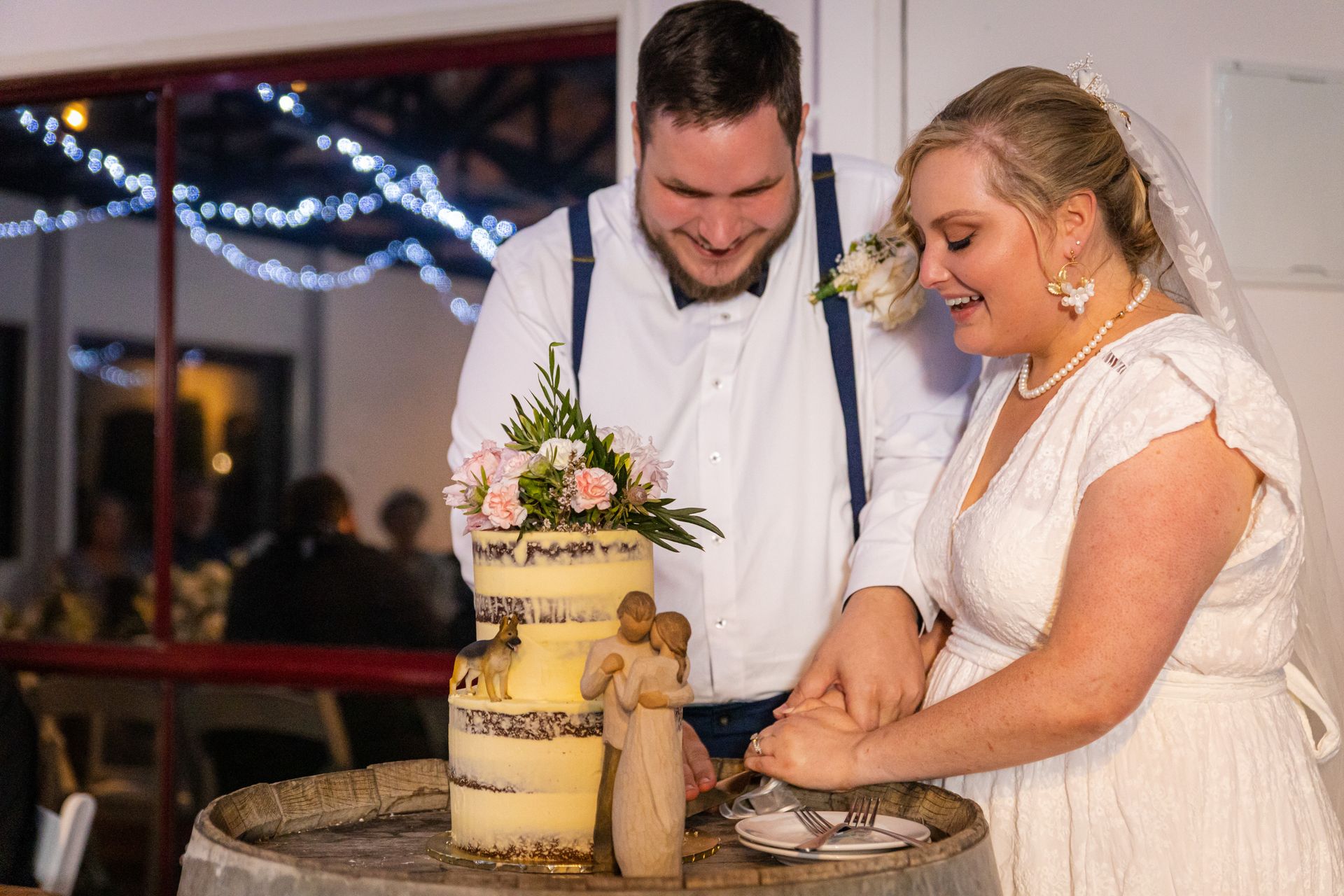 a bride and groom are cutting their wedding cake on a barrel .