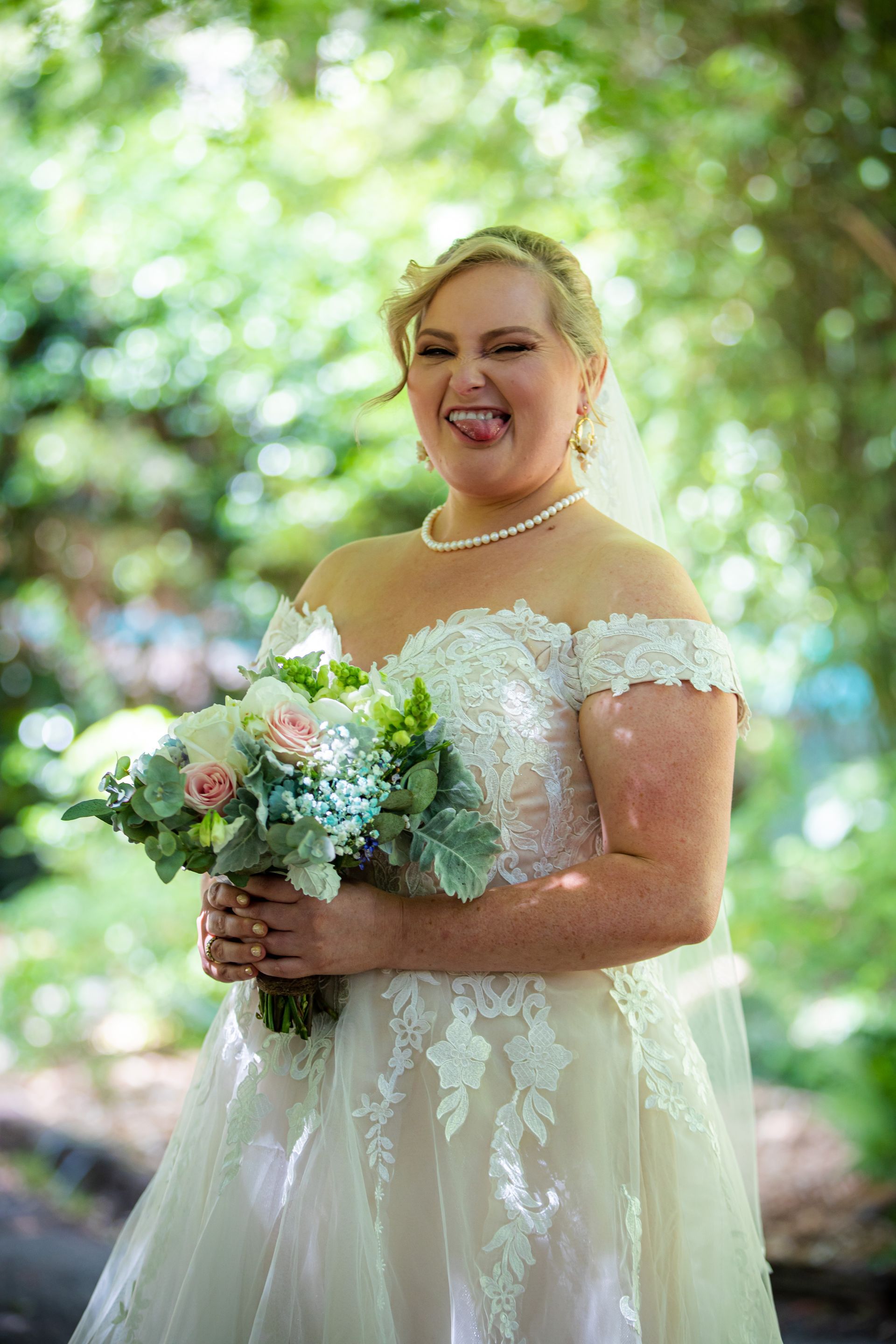 a bride in a wedding dress is holding a bouquet of flowers and sticking her tongue out .
