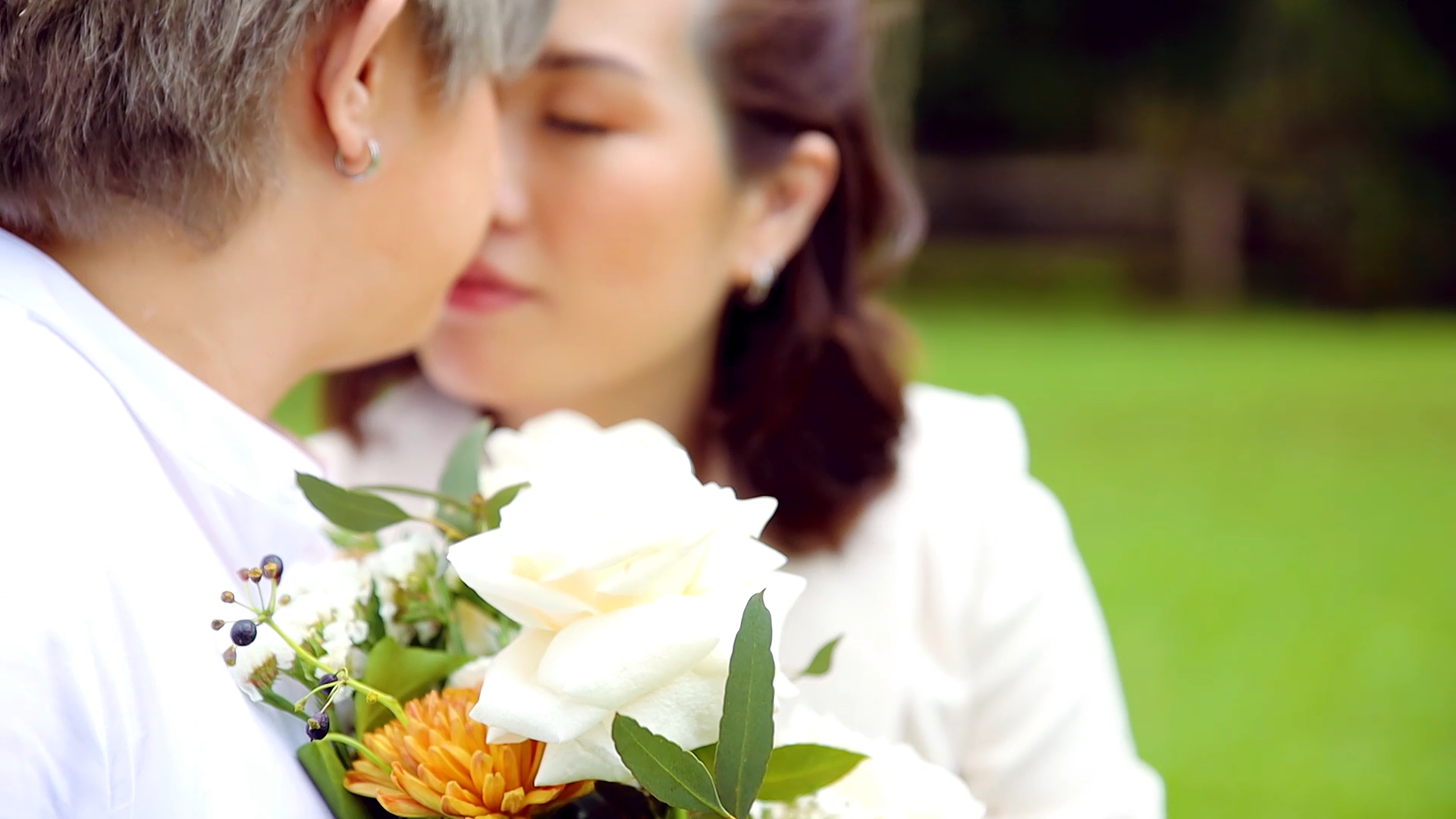 a woman is holding a bouquet of flowers and kissing another woman .