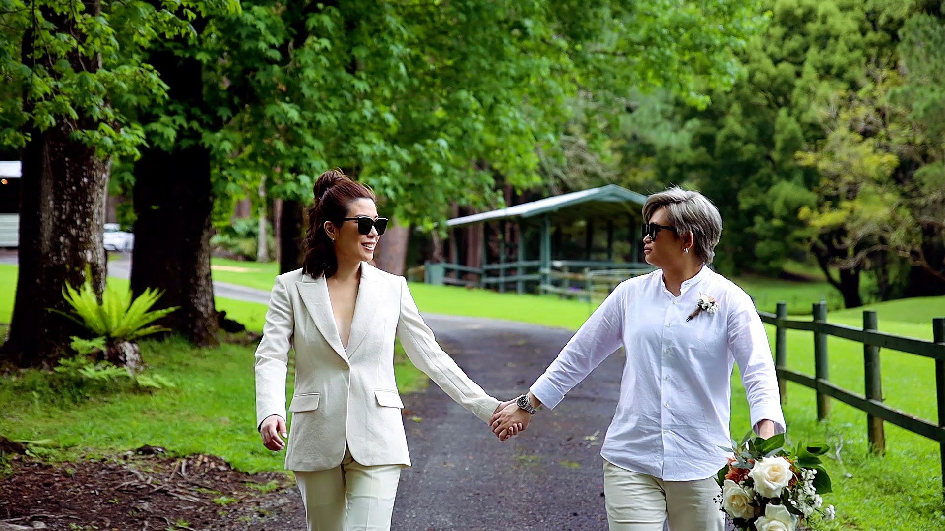 two women are holding hands while walking down a path .